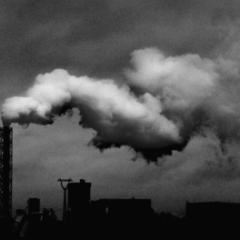 Black and white image of a smoke stack and pollution.